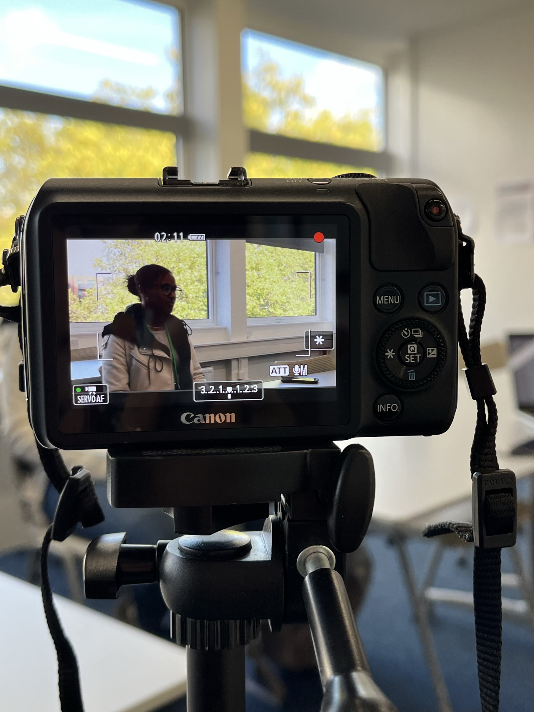 Camera screen recording an interview, mounted on a tripod